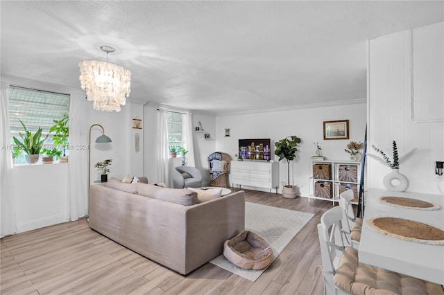 living room featuring a chandelier, light wood-type flooring, and crown molding