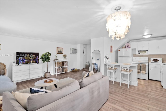 living room featuring a wall unit AC, an inviting chandelier, ornamental molding, and light wood-type flooring