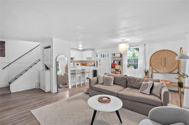 living room featuring a chandelier, light hardwood / wood-style flooring, and crown molding