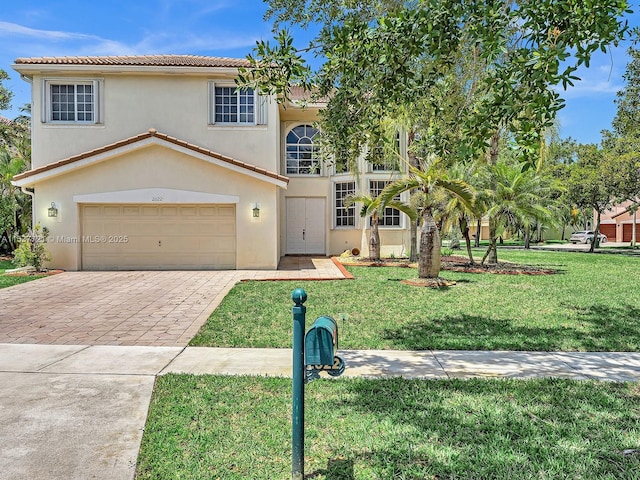 view of front of house with a tiled roof, decorative driveway, a front yard, and stucco siding