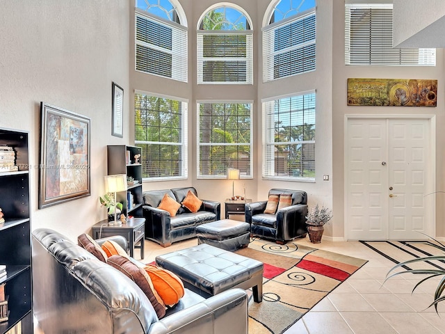 living room with a towering ceiling, light tile patterned floors, plenty of natural light, and baseboards