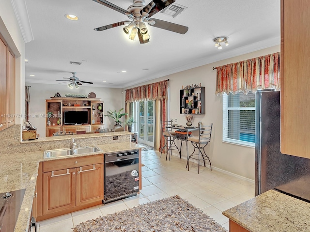 kitchen with a peninsula, a sink, black dishwasher, light countertops, and ornamental molding