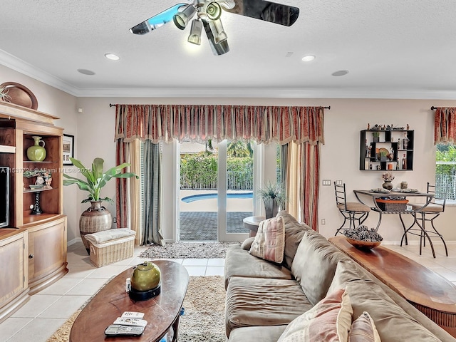 living area with light tile patterned floors, baseboards, a ceiling fan, a textured ceiling, and crown molding