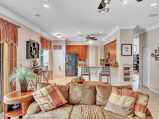 living room featuring visible vents, a ceiling fan, ornamental molding, light tile patterned flooring, and a textured ceiling