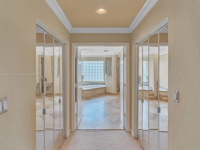 hallway with ornamental molding, light carpet, and a textured wall