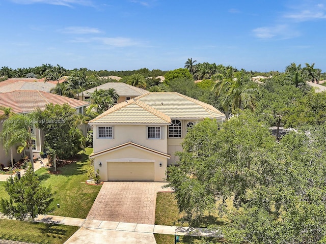 view of front of house featuring a front yard, decorative driveway, a tile roof, and stucco siding