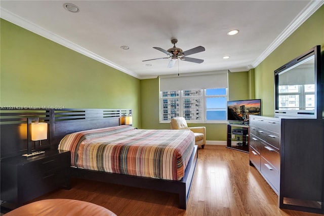 bedroom featuring crown molding, ceiling fan, a water view, and light hardwood / wood-style flooring