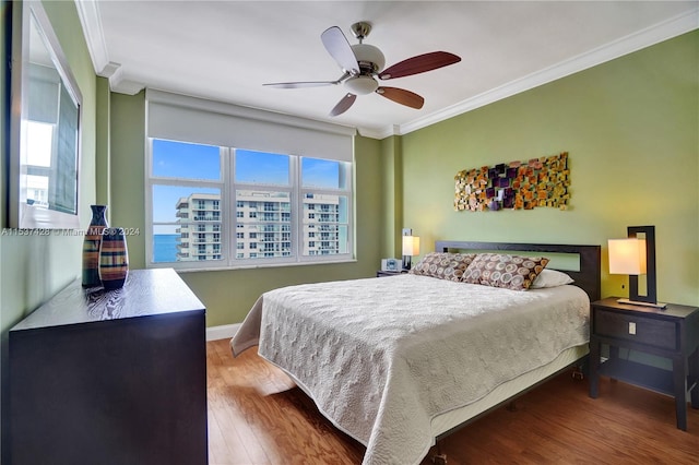 bedroom with ceiling fan, ornamental molding, and wood-type flooring