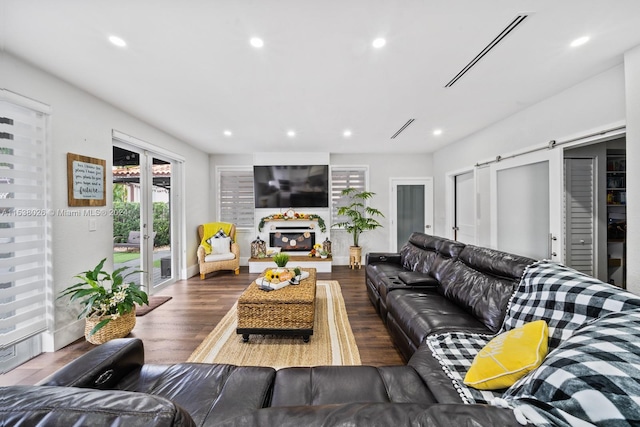 living room featuring a barn door and dark wood-type flooring