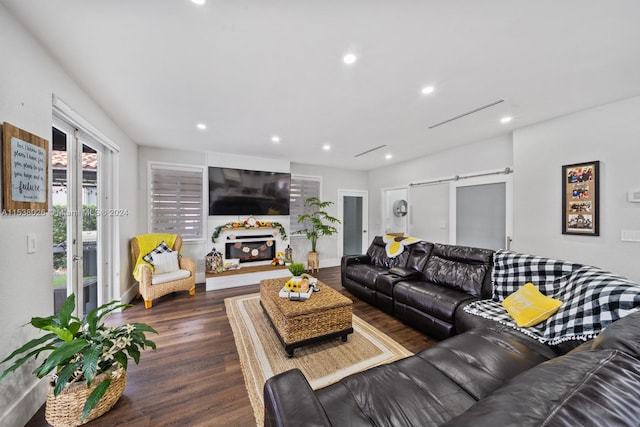 living room with a barn door and dark hardwood / wood-style floors