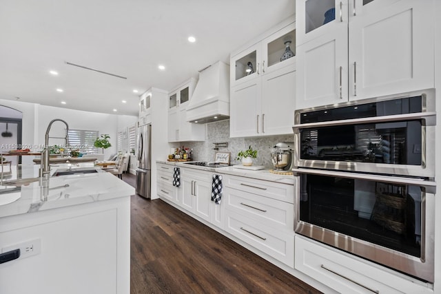 kitchen with appliances with stainless steel finishes, white cabinetry, custom range hood, and dark wood-type flooring