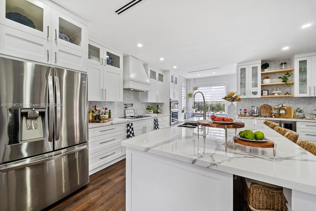 kitchen featuring stainless steel appliances, white cabinets, custom exhaust hood, and light stone counters