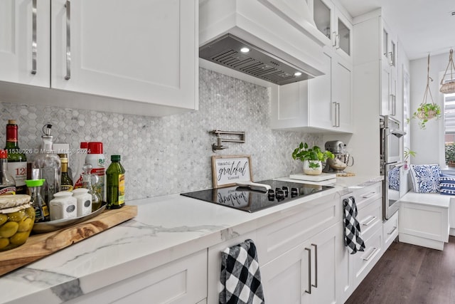 kitchen with dark hardwood / wood-style floors, white cabinets, light stone countertops, custom exhaust hood, and black electric stovetop