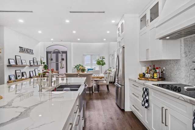 kitchen with light stone counters, custom range hood, stainless steel refrigerator, dark wood-type flooring, and white cabinetry