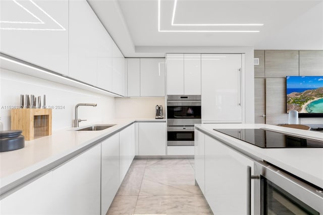 kitchen featuring double oven, light tile floors, beverage cooler, white cabinets, and sink