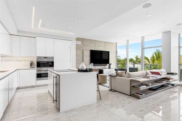 kitchen with expansive windows, white cabinetry, double oven, light tile flooring, and a breakfast bar area