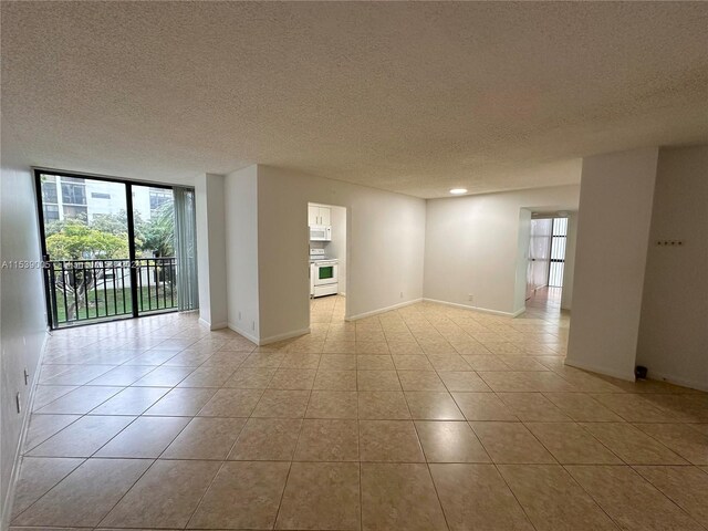 unfurnished room featuring a wall of windows, light tile floors, and a textured ceiling