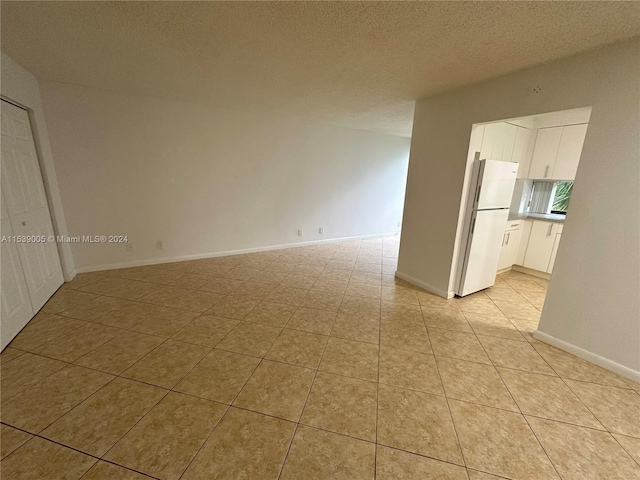 tiled empty room with a textured ceiling