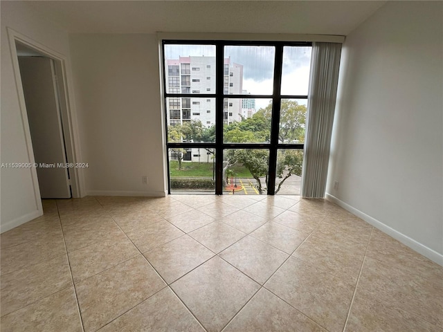 empty room with floor to ceiling windows and light tile floors