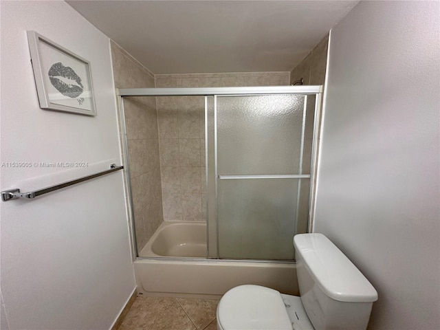 bathroom featuring combined bath / shower with glass door, toilet, and tile flooring