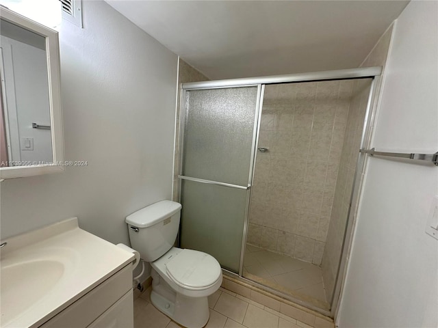 bathroom with tile floors, toilet, vanity, and a shower with door