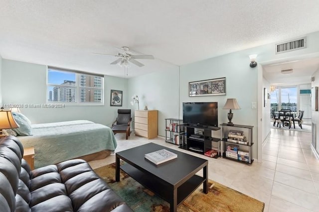 tiled bedroom featuring ceiling fan and a textured ceiling