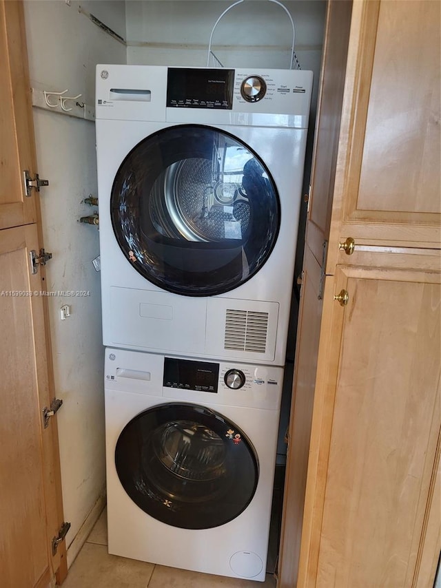 clothes washing area with stacked washer and clothes dryer and light tile patterned floors