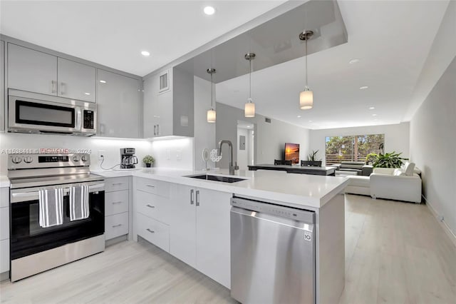 kitchen featuring hanging light fixtures, appliances with stainless steel finishes, gray cabinetry, and light hardwood / wood-style flooring