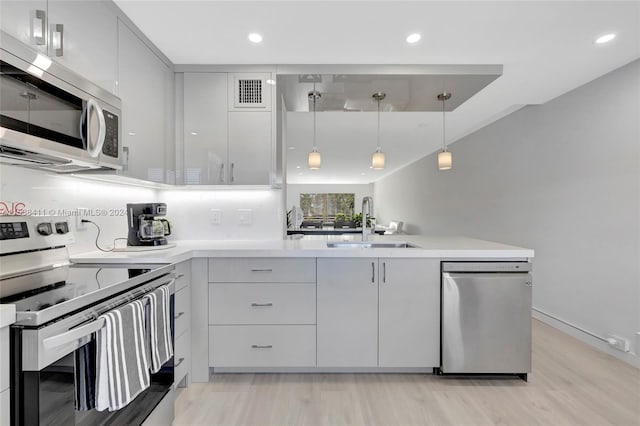 kitchen featuring decorative light fixtures, stainless steel appliances, light hardwood / wood-style floors, tasteful backsplash, and sink