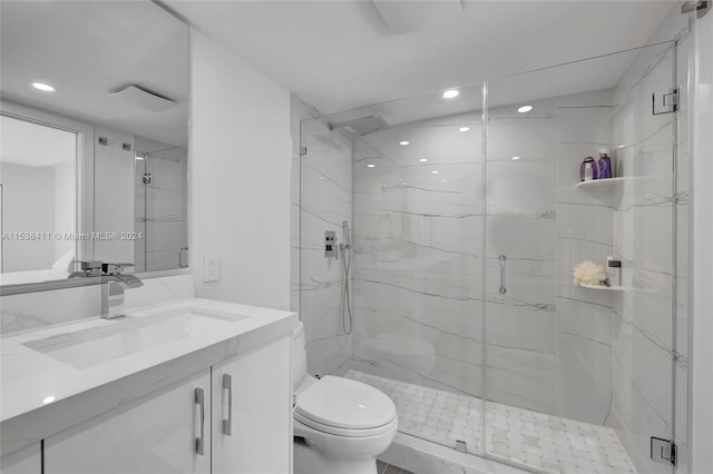 bathroom featuring a shower with door, vanity, and toilet