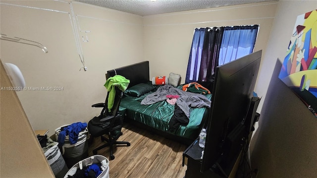 bedroom with a textured ceiling and light wood-type flooring