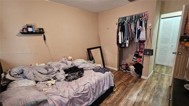 bedroom with a closet, dark hardwood / wood-style floors, and a textured ceiling