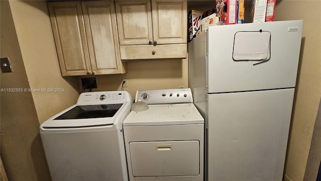 clothes washing area with cabinets and washing machine and clothes dryer