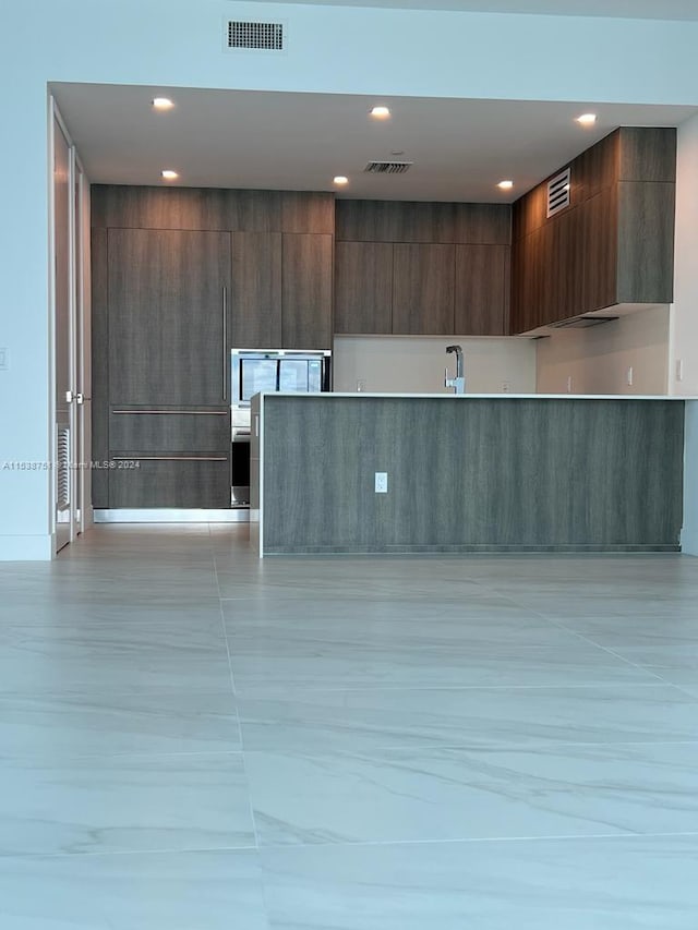 kitchen featuring light tile floors and dark brown cabinets