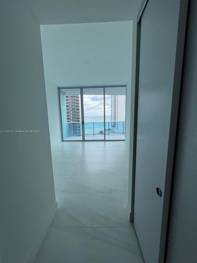 hallway with expansive windows, light tile floors, and a water view