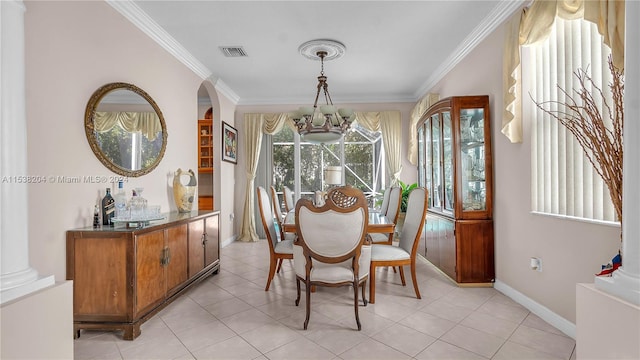 tiled dining area featuring an inviting chandelier, ornate columns, and ornamental molding