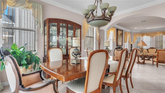 tiled dining space with a notable chandelier, crown molding, and ornate columns