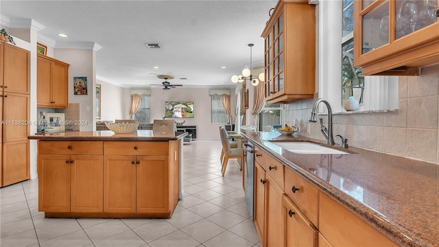 kitchen with pendant lighting, dark stone counters, ceiling fan with notable chandelier, tasteful backsplash, and sink