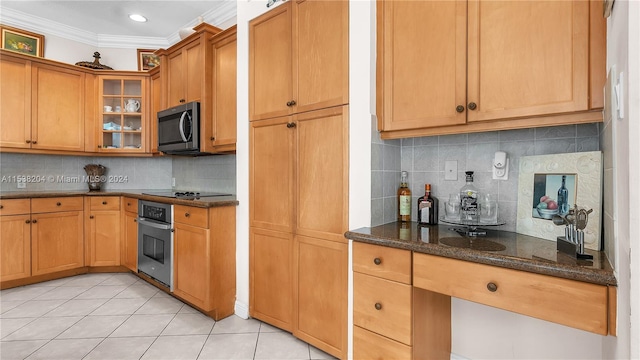 kitchen with light tile floors, appliances with stainless steel finishes, crown molding, backsplash, and dark stone countertops