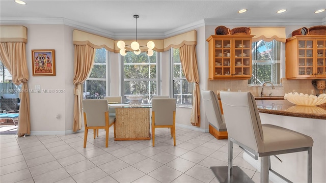 tiled dining room with a notable chandelier, sink, and ornamental molding