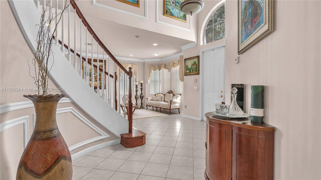 tiled entryway with crown molding and a towering ceiling