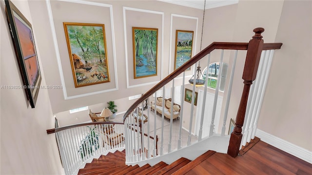 stairs with crown molding, a high ceiling, a wealth of natural light, and hardwood / wood-style flooring