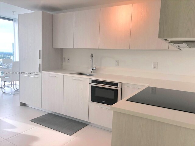 kitchen featuring sink, light tile patterned floors, range hood, black electric cooktop, and stainless steel oven