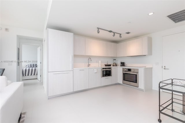 kitchen featuring sink, rail lighting, and stainless steel oven