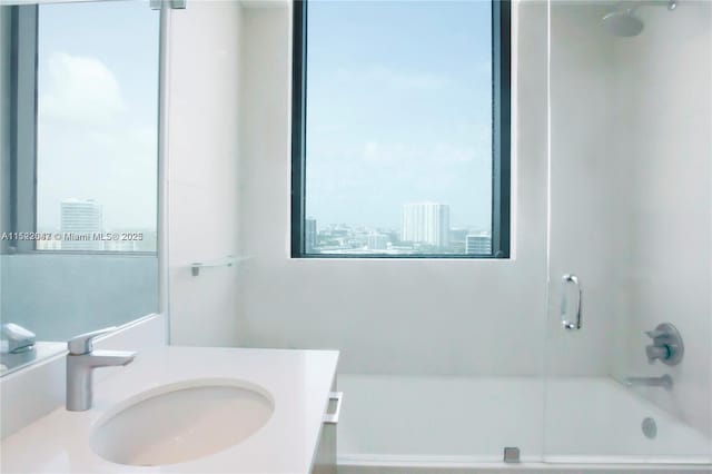 bathroom featuring bath / shower combo with glass door and vanity