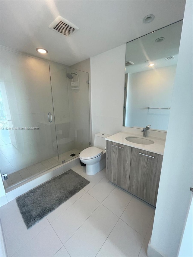 bathroom with tile patterned flooring, vanity, a shower with door, and toilet