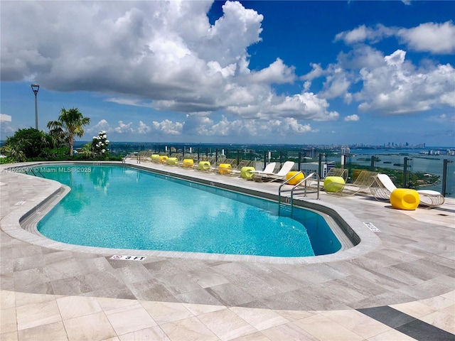 view of swimming pool with a patio and a water view