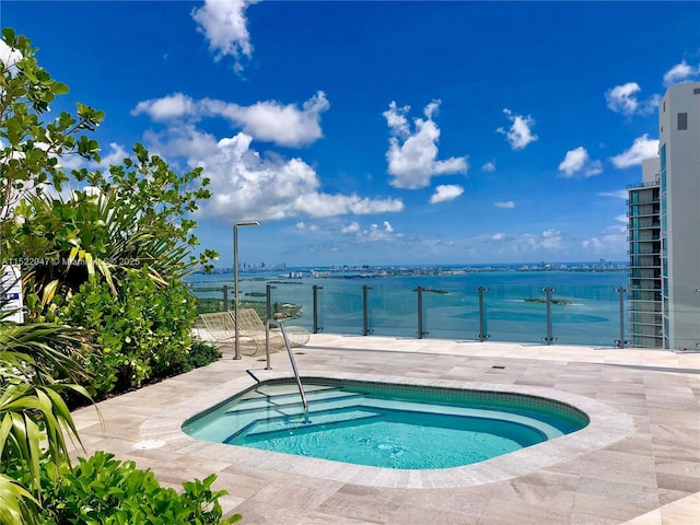 view of pool featuring a patio area, an in ground hot tub, and a water view