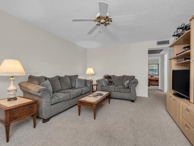 carpeted living room with ceiling fan and a textured ceiling