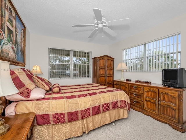 bedroom with ceiling fan, carpet floors, multiple windows, and a textured ceiling